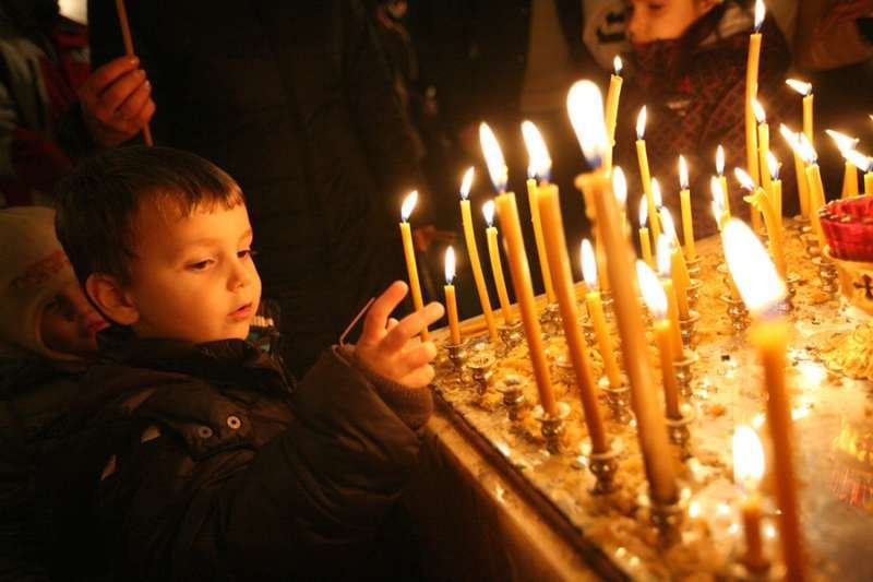 A child lights a candle at Christmas Mass. Credit: haak78