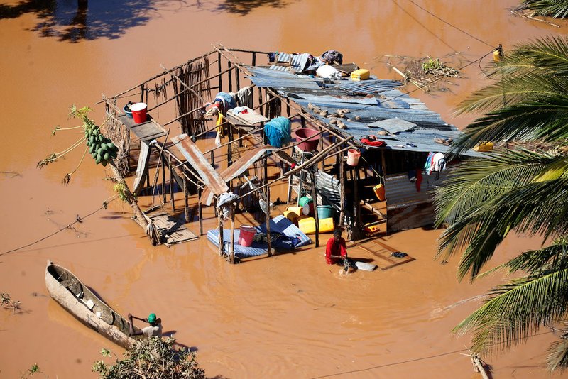 A man paddles his canoe past a destroyed home March 21