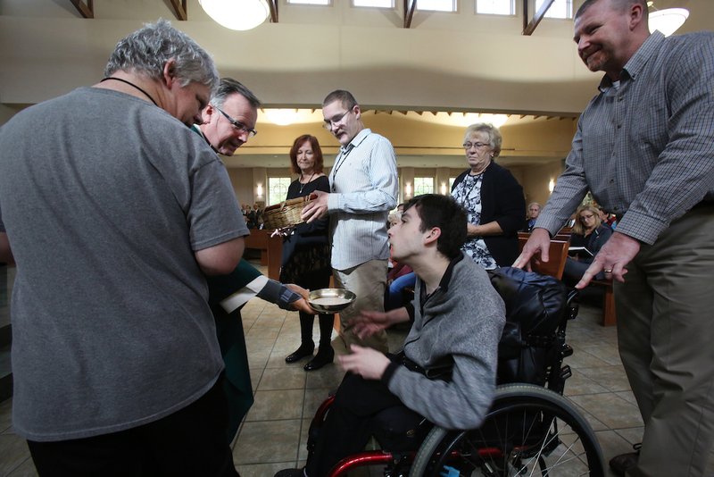 Father John Dakes, pastor of Jesus the Divine Word Church in Huntington, Md., accepts the gifts from Ben Lash during an Oct. 28 Mass for people with special needs. All the people with special needs were given a role in the Mass. (CNS photo/Bob Roller)