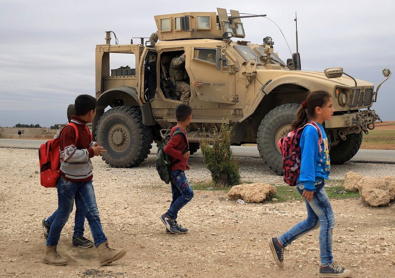 Syrian schoolchildren walk as U.S. troops patrol in Hassakeh