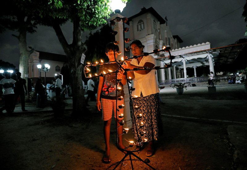 People light oil lamps outside St. Sebastian Church in Negombo