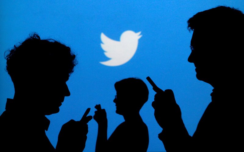 People use mobile phones in front of the Twitter logo in this 2013 illustration photo. (CNS photo/Kacper Pempel