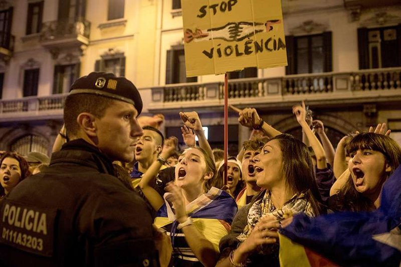 A Catalan police officer stands_in front protestors against yesterdays referendum vote on October 2