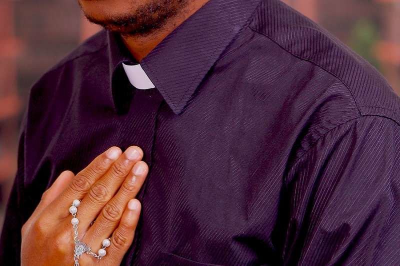 African priest praying rosary. Credit: Fotos593/Shutterstock.