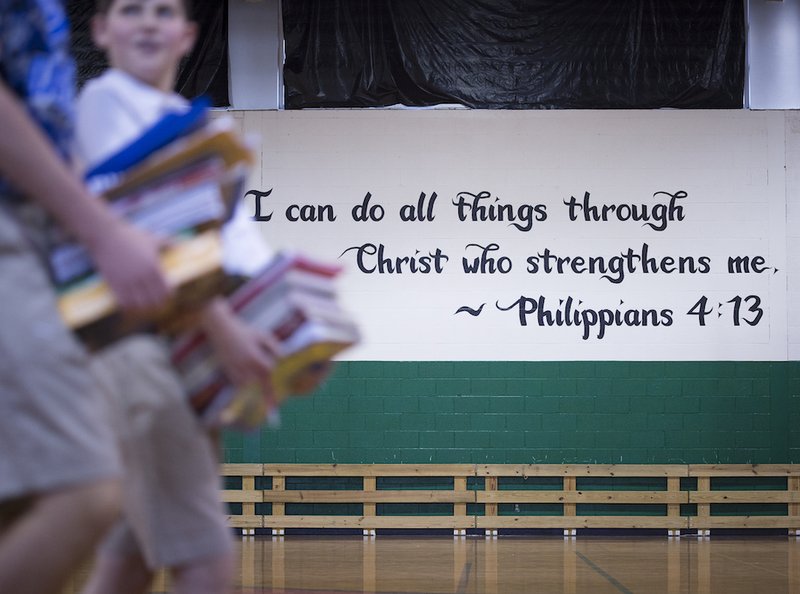 A quote from the New Testament is seen March 29 near students carrying their books to class at Holy Name of Jesus Catholic School in Henderson