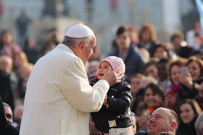 Pope francis kisses a child in St. Peter's Square for the general audience Dec. 9