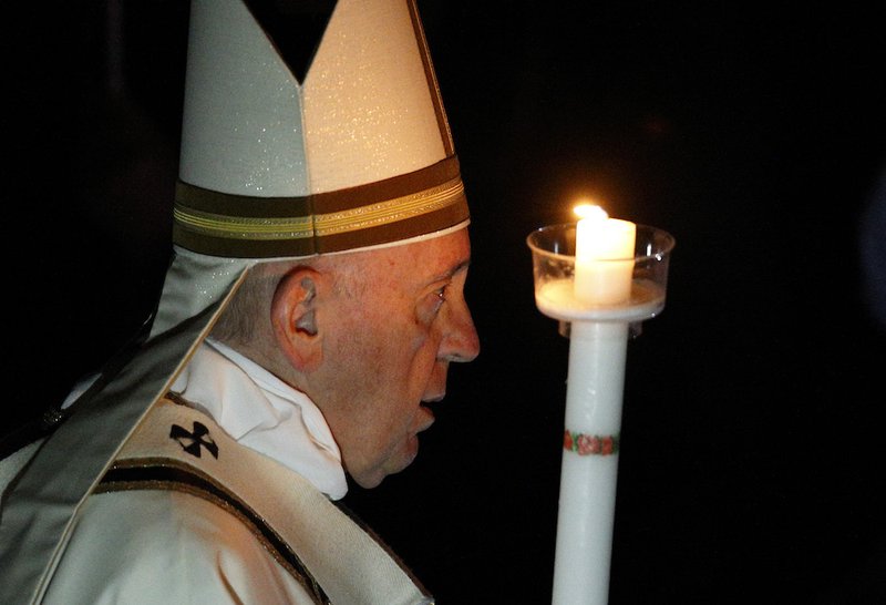 Pope Francis carries a candle in procession as he arrives to celebrate the Easter Vigil in St. Peter's Basilica at the Vatican April 20