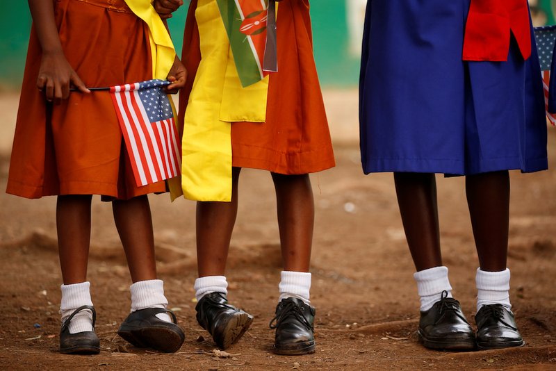 Girls hold U.S. and Kenyan flags as they wait to greet U.S. Ambassador to Kenya Robert Godec as he visits a President's Emergency Plan for AIDS Relief project for girls' empowerment in early March in Nairobi