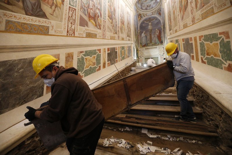 Notes from pilgrims are seen as workers remove a wooden covering over the Holy Stairs at the Pontifical Sanctuary of the Holy Stairs in Rome March 15