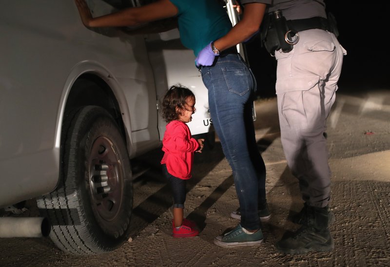 A two-year-old Honduran asylum seeker cries as her mother is searched and detained near the U.S.-Mexico border on June 12