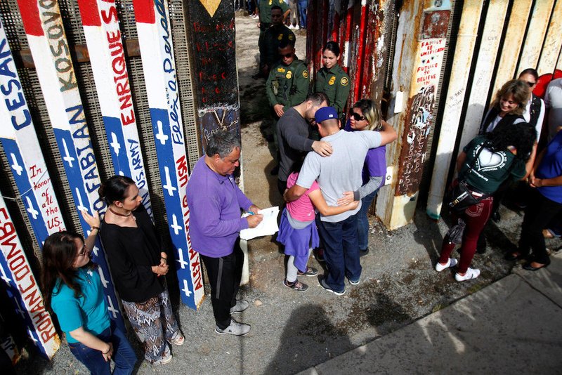 U.S. Border Patrol agents open a single gate to allow families to hug and talk along the U.S.-Mexico border in Tijuana