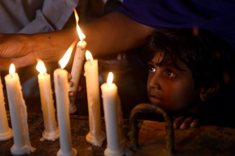 A Pakistani Christian child looks on as adults light candles to pay tribute to Sri Lankan blasts victims in Karachi on April 21