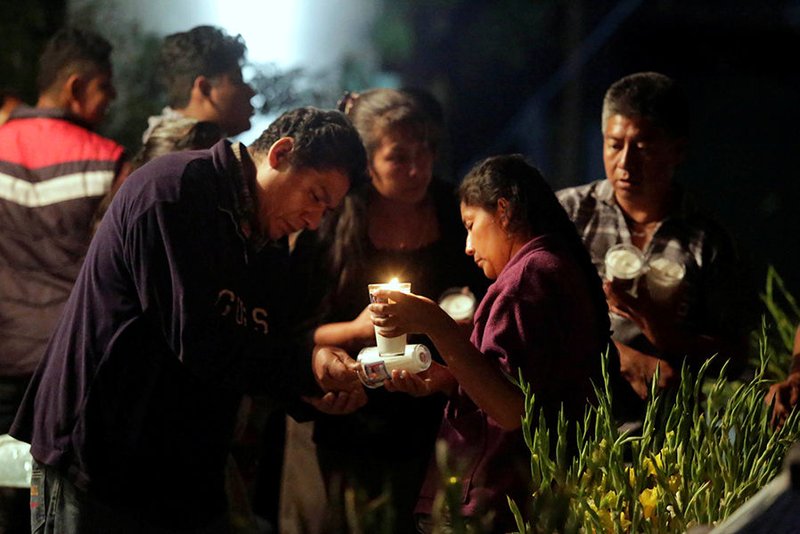 People light candles Sept. 20 for the 11 victims who died after the roof of a church collapsed following an earthquake in Atzala