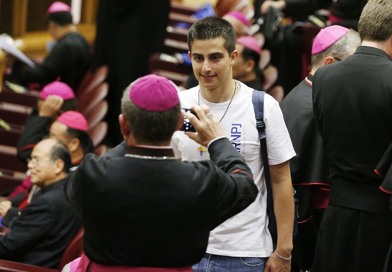 A bishop takes a photo of a youth delegate before the opening session of the Synod of Bishops on young people