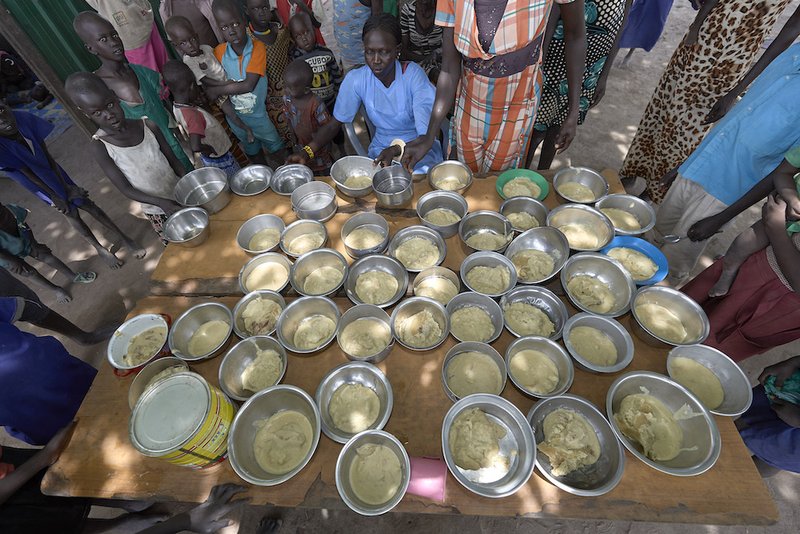 Kana Achot fills bowls with food in an emergency feeding program for malnourished children at the Loreto Girls School in Rumbek