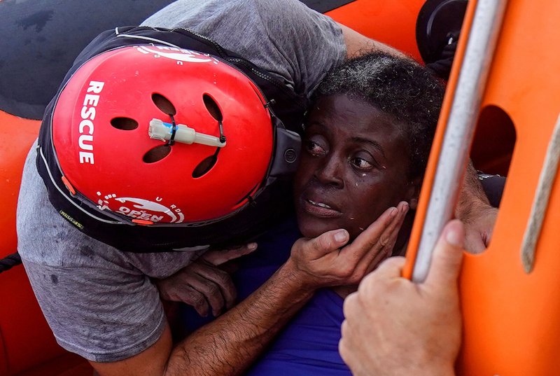 A crew member of the Spanish nongovernmental organization Proactiva Open Arms comforts a rescued African migrant July 17 in central Mediterranean Sea. The main mission of the NGO is sea rescues of refugees that arrive in Europe fleeing wars