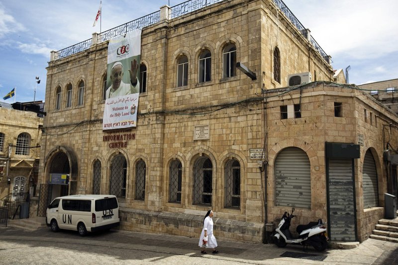 A nun walks past a banner with an image of Pope Francis hanging on the Christian Information Center building in Jerusalem's Old City in 2014. (CNS file photo/Amir Cohen