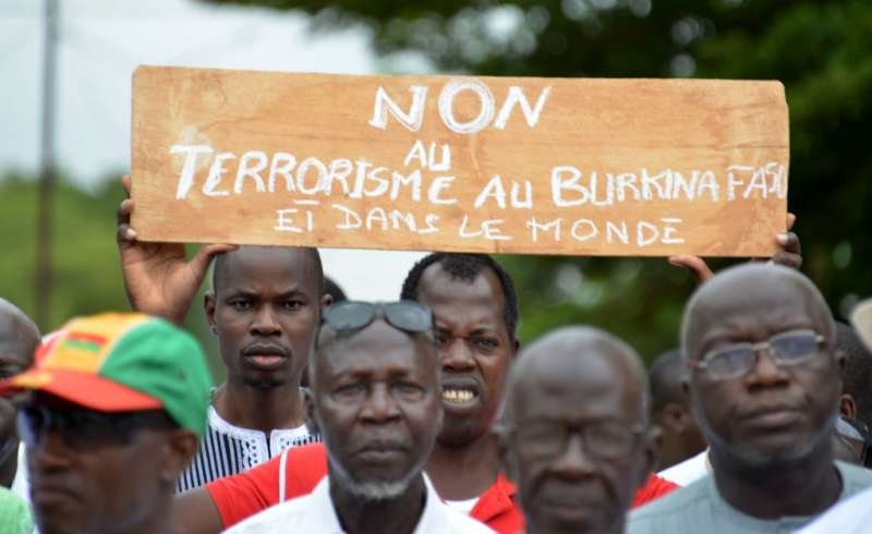 Protestors march holding a placard they take part in a rally "no to barbarism" in central Ouagadougou on August 19