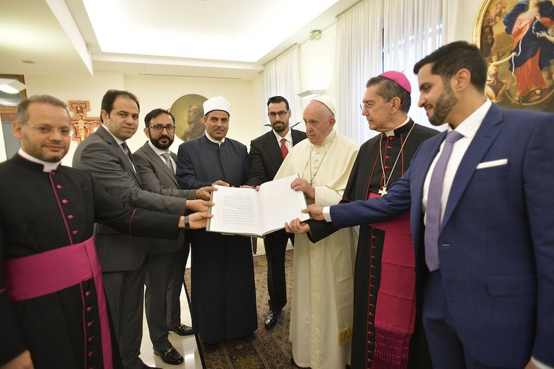 Pope Francis and members of the committee working to fulfill the goals of the "Document on Human Fraternity for World Peace and Living Together" hold a special copy of the document issued by the Vatican Library Sept. 11