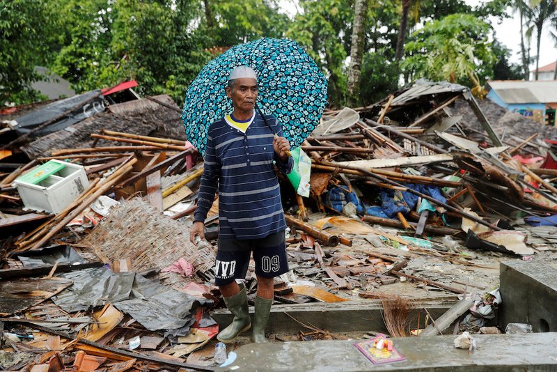 An Indonesian man walks through the debris of his destroyed house in Sumur Dec. 26 after a tsunami hit two islands. Indonesian authorities asked people to avoid the coast in areas where the tsunami killed more than 400 people. (CNS photo/Jorge Silva