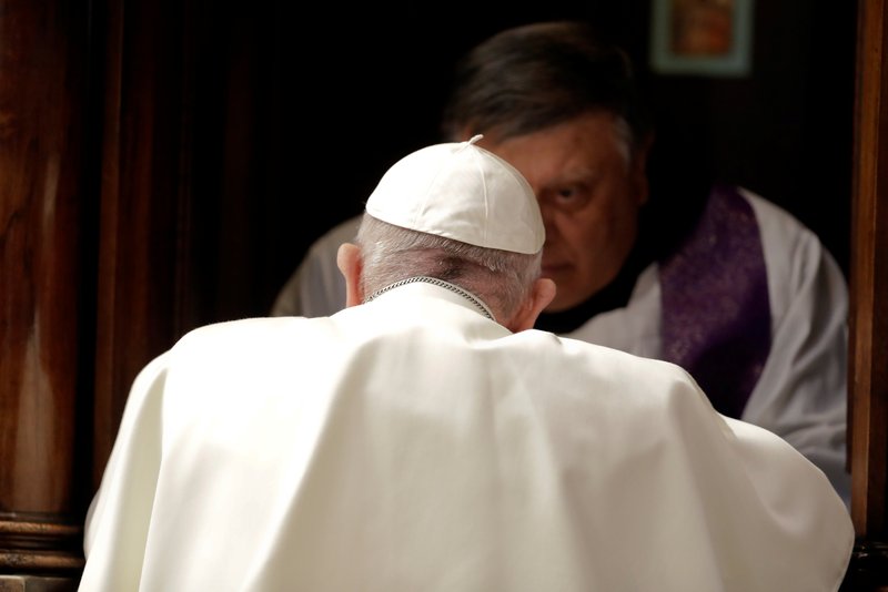 A priest hears Pope Francis' confession during a Lenten penance service in St. Peter's Basilica at the Vatican March 29