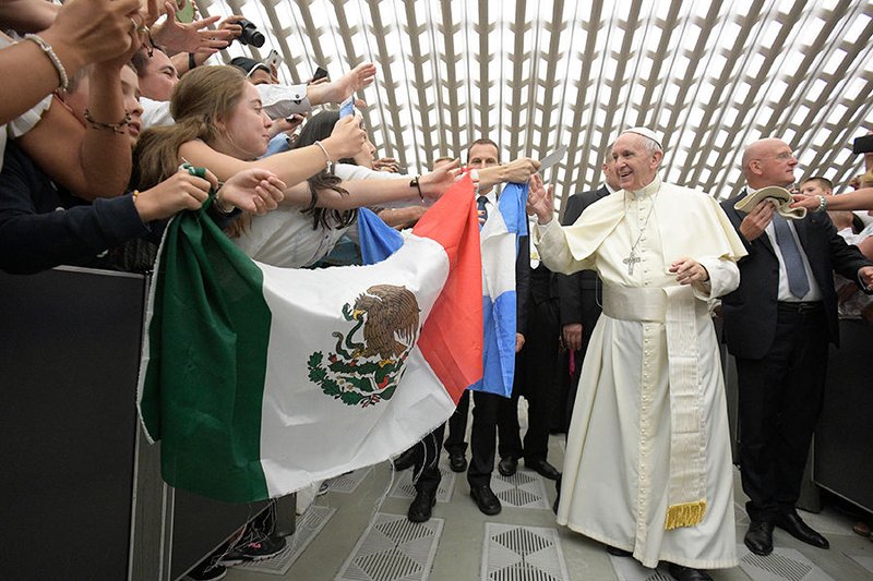 Pope Francis greets pilgrims holding Mexico's flag as he arrives for his weekly audience in Paul VI hall at the Vatican Aug. 23. (CNS photo/L'Osservatore Romano)