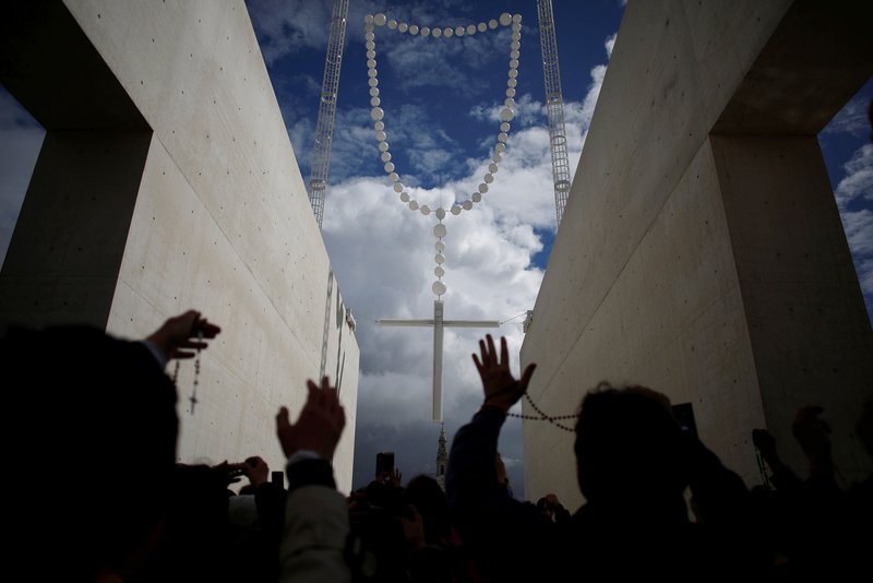 Pilgrims pray near a large rosary May 11 at the Shrine of Our Lady of Fatima in central Portugal. Pope Francis will canonize Blessed Jacinta Marto and Blessed Francisco Marto