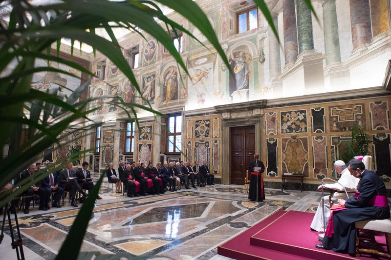 Pope Francis listens as Cardinal Peter Turkson
