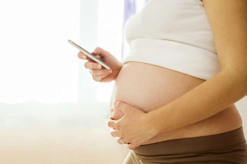 Pregnant woman with mobile phone. Via Shutterstock