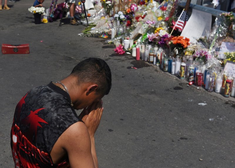 A man prays at a memorial Aug. 6 three days after a mass shooting at a Walmart store in El Paso