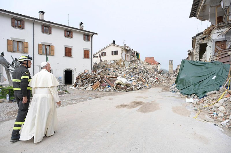 Pope Francis walks with a firefighter as he visits the earthquake-ravaged town of Amatrice