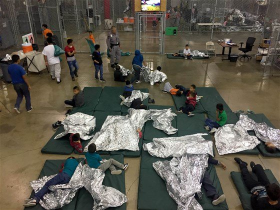 Migrant children lay on mats on the floor