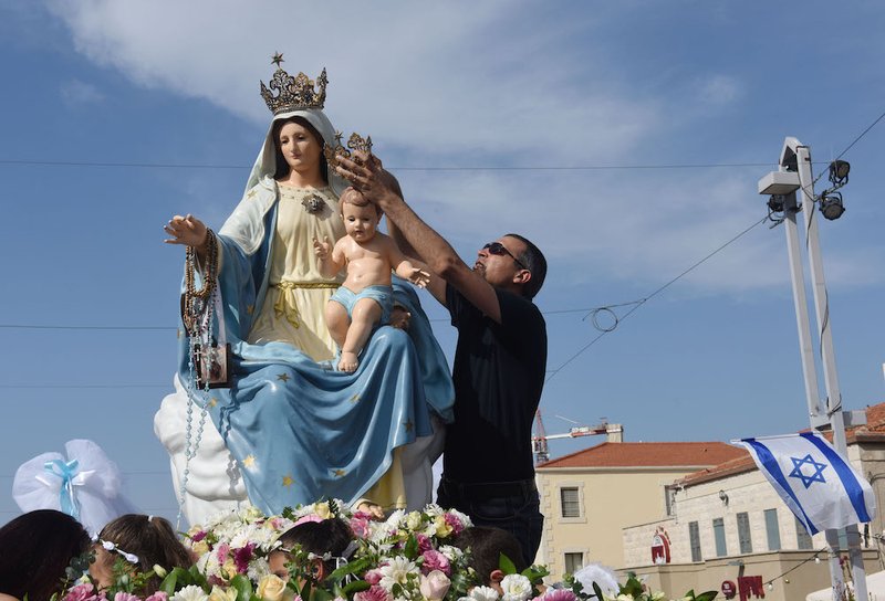 A worshipper touches the statue of Our Lady of Carmel and the Christ Child during a procession outside the Church of St. Joseph in Haifa, Israel, May 5, 2019. (CNS photo/Debbie Hill) See MOUNT-CARMEL-CENTENNIAL-STATUE May 6, 3029.