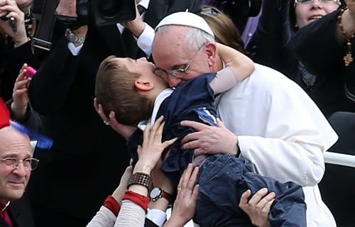 Pope Francis embraces a boy prior to his first 'Urbi et Orbi' blessing on Easter Sunday