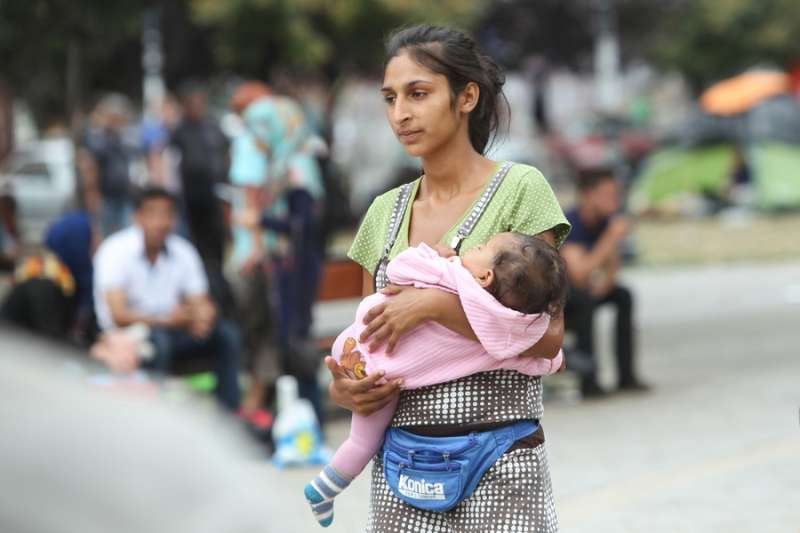 A young woman waits with her child by the train station in Belgrade