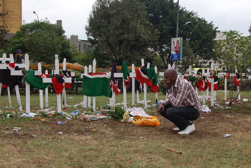 A man kneels at a site in Uhuru Park where activists erected crosses to remember the students killed during the 2015 attacks at Kenya's Garissa University College. As frequent terror attacks continue in northeastern Kenya