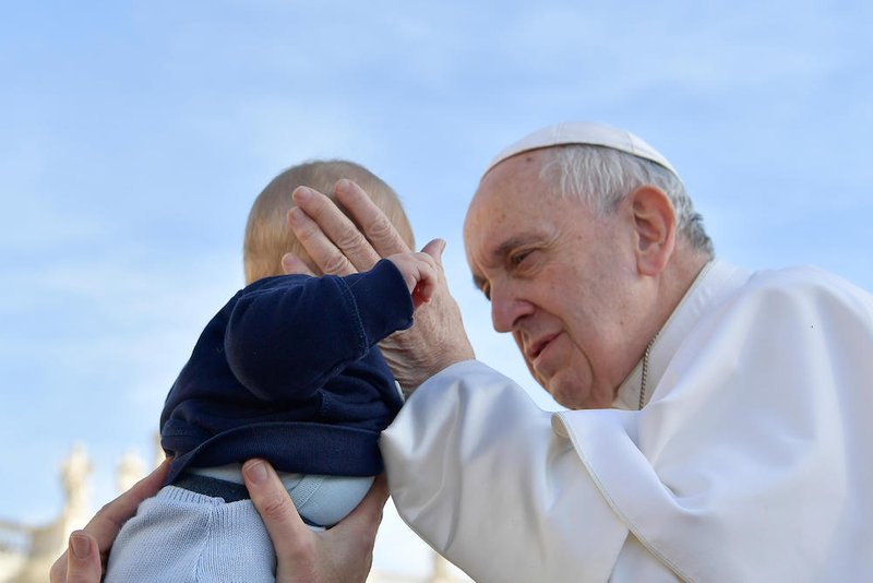Pope Francis greets a baby as he arrives for his general audience in St. Peter's Square at the Vatican Feb. 27
