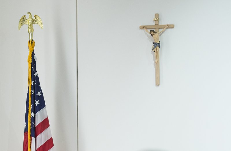 People sit near a U.S. flag and a cross Nov. 5 at the St. John Paul II National Shrine in Washington. The International Religious Freedom Act celebrated 20 years this year. (CNS photo/Tyler Orsburn)
