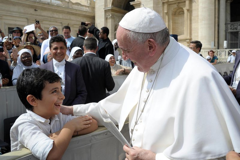 Pope Francis greets a child as he arrives for his general audience in St. Peter's Square at the Vatican Aug. 28