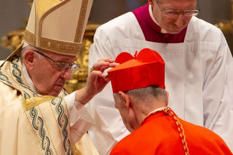 Pope Francis places a red biretta on the head of a new cardinal during a consistory held in St. Peter's Basilica