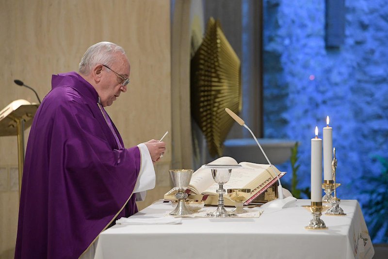 Pope Francis holds the Eucharist during morning Mass in the chapel of his residence