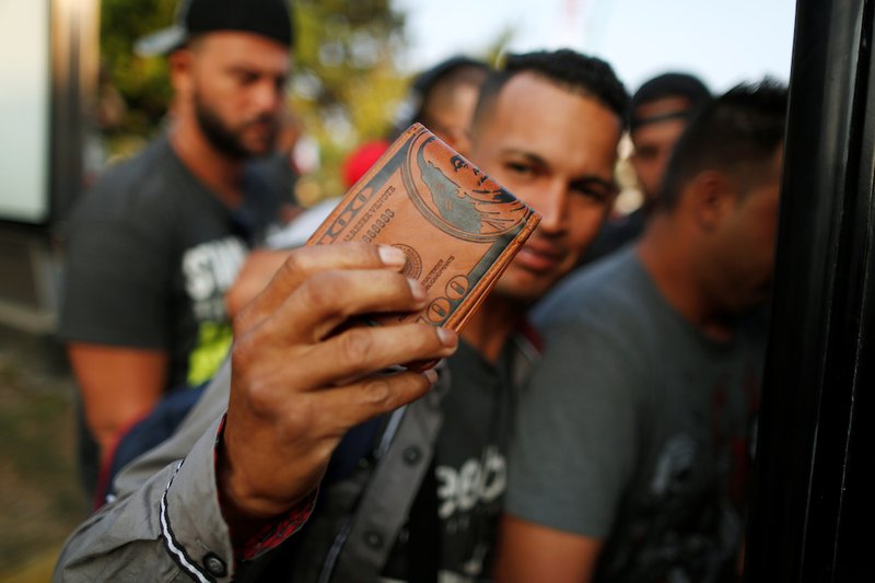 A migrant shows his wallet while boarding a bus in Tapachula