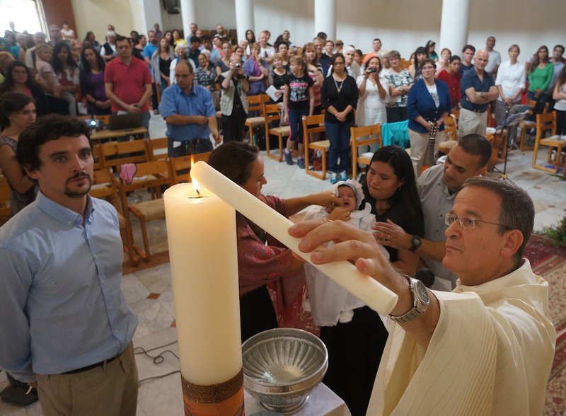 Jesuit Father David Neuhaus lights a baptismal candle during a Mass for Hebrew-speaking Catholics in Israel in 2014. (CNS photo/courtesy www.catholic.co.il)