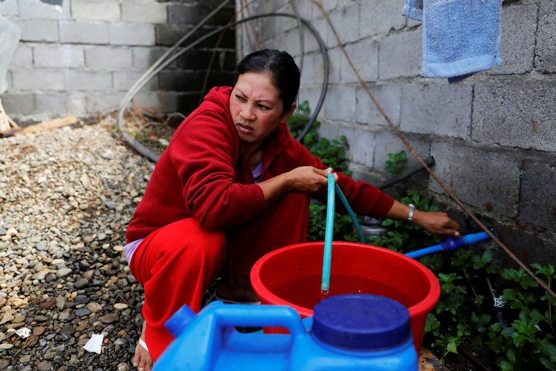 A woman fills containers with water at the only water source near the school-turned-evacuation center in Marawi City