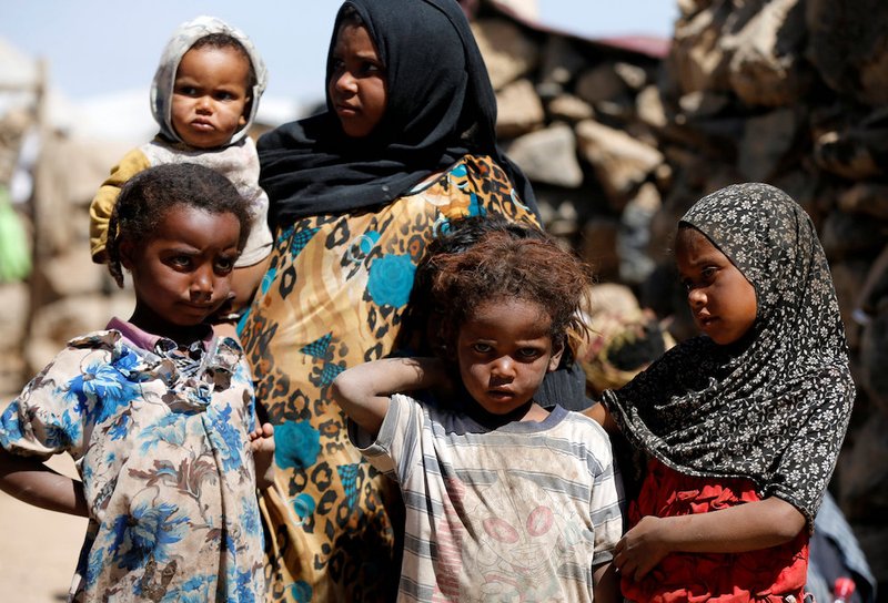 A woman stands with children at a makeshift camp for internally displaced people near Sanaa
