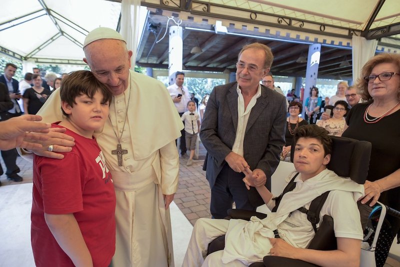 Pope Francis embraces a young man as he visits a center for the severely disabled outside of Rome June 24. (CNS photo/Vatican Media)