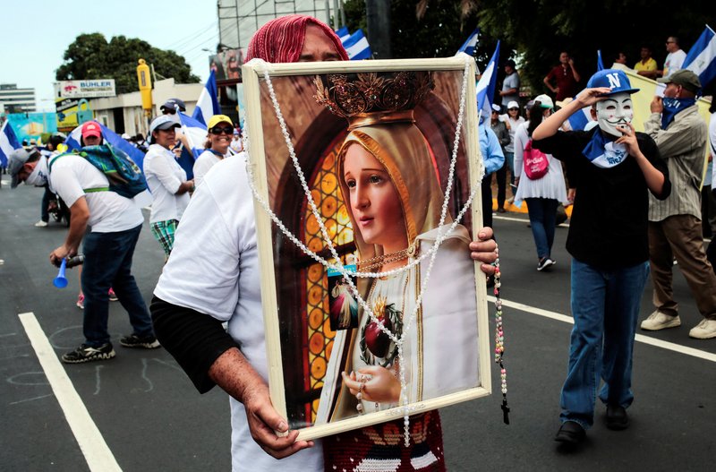 A demonstrator holds a picture of Mary during a march in support of the Catholic Church July 28 in Managua
