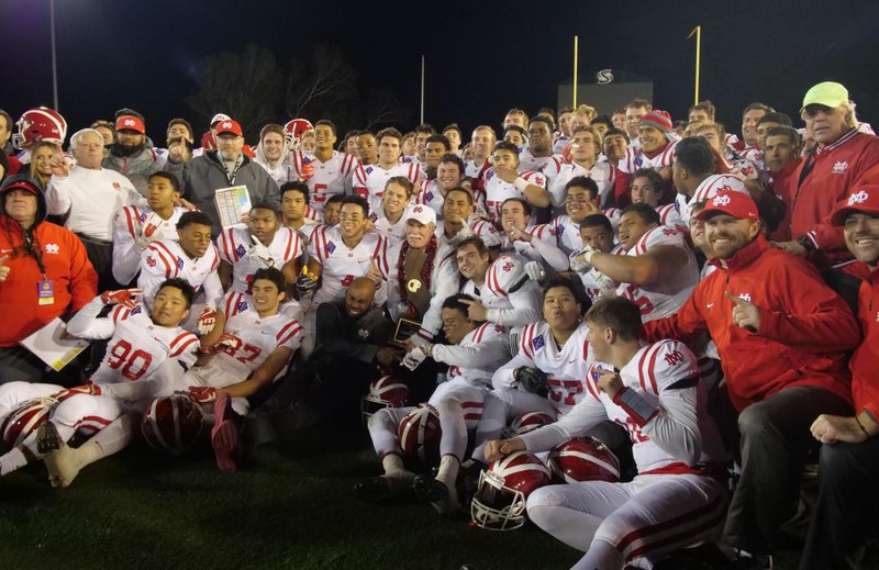 Head Coach Bruce Rollinson is surrounded by Mater Dei players and coaches after the Monarchs won their first CIF state championship in football