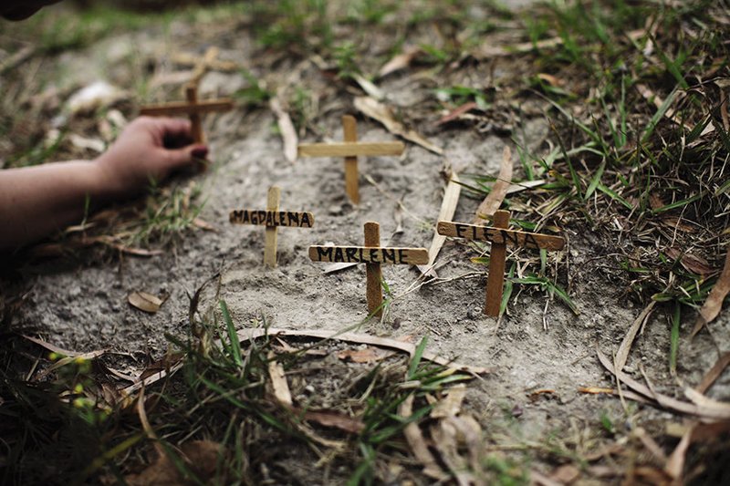 A woman sets crosses in front of a courthouse with the names of slain women during a march to mark International Women’s Day in San Salvador