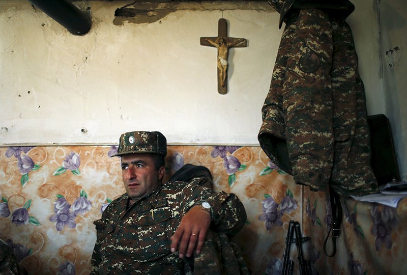An ethnic Armenian soldier rests beneath a crucifix April 7